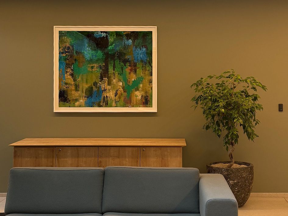 Green Valley, framed abstract in deep greens and blues, installed above a wooden sideboard.